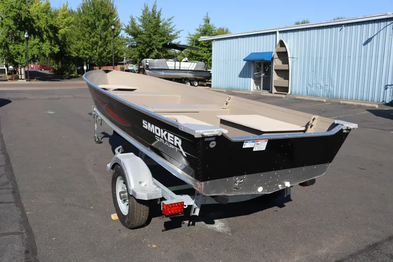 Slide: The Image of 2025 Smoker Craft Voyager 16 boat on trailer, parked outdoors near blue building. - 4