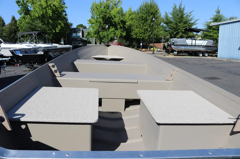 Slide: The Image of 2025 Smoker Craft Voyager 16 boat interior with seating and storage, parked outdoors. - 5