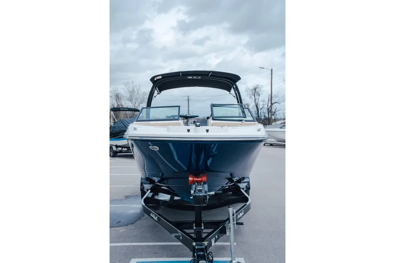 Slide: The Image of 2024 Sea Ray SPX 230 boat on trailer, parked outdoors under cloudy sky. - 2