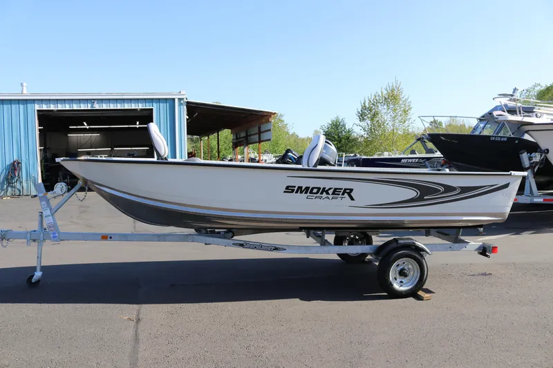 The Image of 2025 Smoker Craft Angler 16 XL TL boat on trailer, parked outdoors. - 1