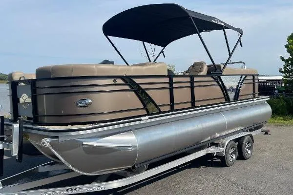The Image of 2024 Veranda VTX 22RC pontoon boat with canopy on a trailer, parked near water. - 0