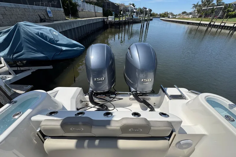 Slide: The Image of 2022 Key West 244 Center Console boat with twin Yamaha 150 engines docked by a canal. - 11