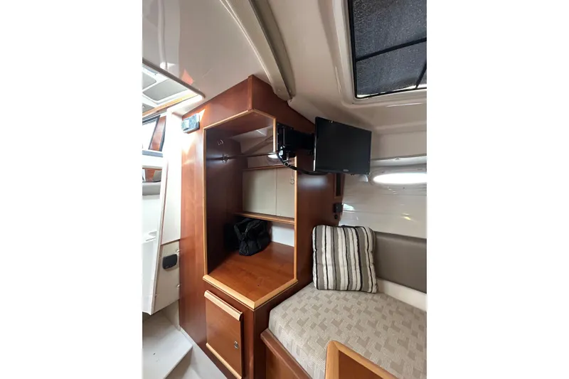 Slide: The Image of 2024 Cutwater C-288 Coupe interior with wood cabinetry, TV, and cozy seating area. - 25