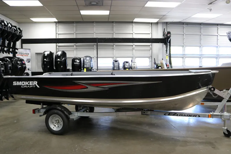 The Image of 2025 Smoker Craft Big Fisherman 14 boat on trailer in showroom. - 1