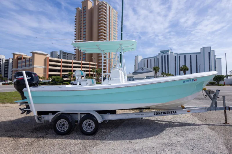 Slide: The Image of 2007 Andros Cuda 23 boat on trailer, parked near tall buildings under a clear sky. - 5