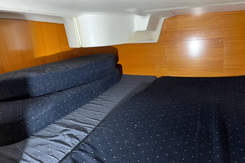 Slide: The Image of Interior cabin of 1999 Beneteau First 42s7 sailboat with dark cushions and wooden paneling. - 18