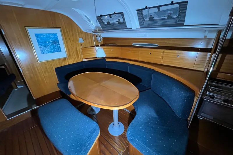Slide: The Image of Interior of 1999 Beneteau First 42s7 yacht with curved seating and wooden table. - 9
