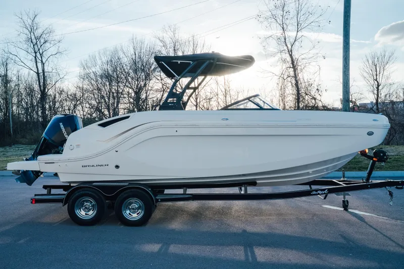 The Image of 2023 Bayliner DX 2200 boat on trailer, parked outdoors with trees in background. - 0