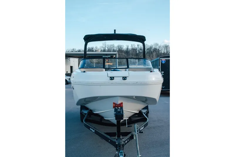 Slide: The Image of 2023 Bayliner DX 2200 boat on trailer, front view, outdoors. - 2