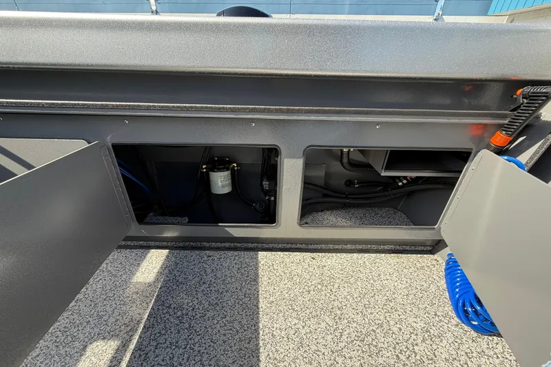 Slide: The Image of 2025 Alumaweld Stryker X202 boat interior storage compartments with visible wiring and equipment. - 23