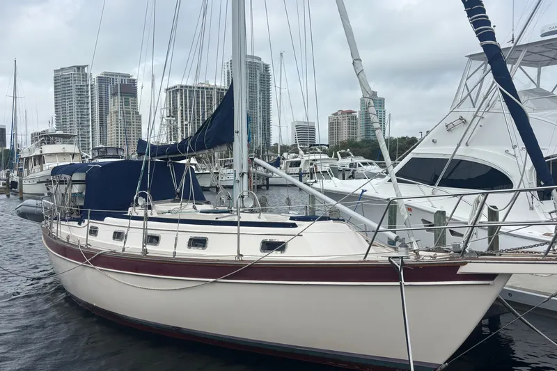 The Image of 1995 Island Packet 37 sailboat docked in marina with city skyline background. - 0