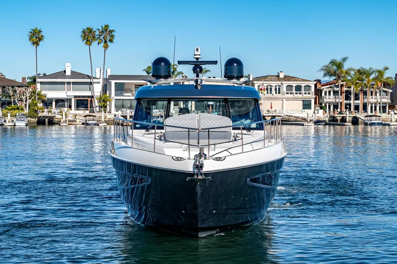 Slide: The Image of 2024 Riviera 5400 Sport Yacht in a marina with waterfront homes. - 13