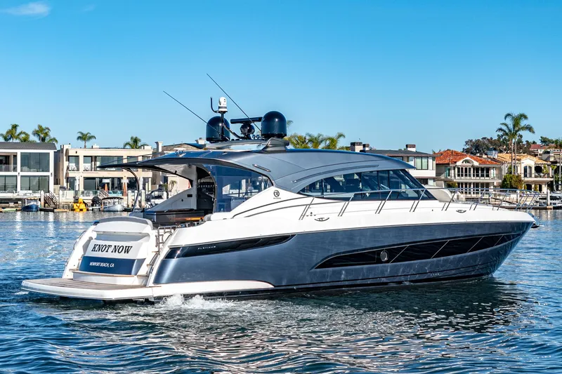 Slide: The Image of 2024 Riviera 5400 Sport Yacht cruising in a marina with waterfront homes in the background. - 17