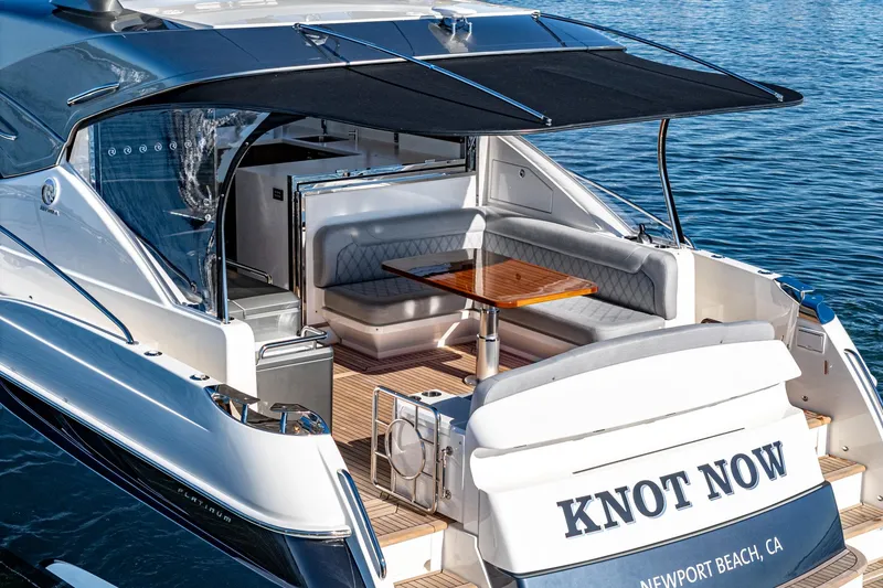 Slide: The Image of 2024 Riviera 5400 Sport Yacht with shaded seating area, named Knot Now, docked in Newport Beach, CA. - 21