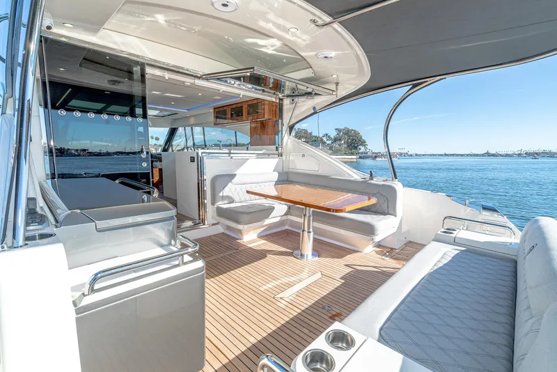 Slide: The Image of 2024 Riviera 5400 Sport Yacht, spacious deck with seating and dining area, overlooking the water. - 25