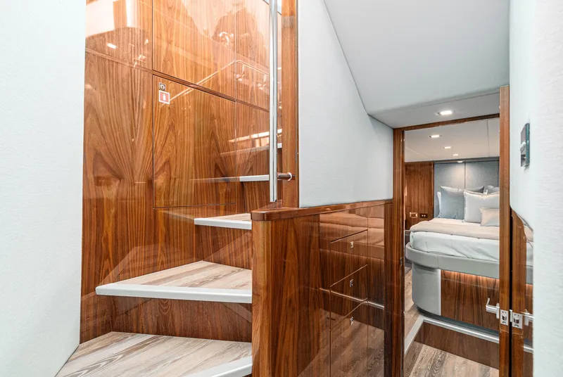 Slide: The Image of 2024 Riviera 5400 Sport Yacht interior with wooden stairs and luxurious bedroom. - 47