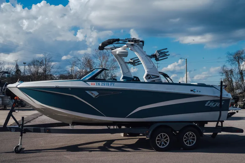 Slide: The Image of 2023 Tigé Z1 boat on trailer under cloudy sky, side view. - 1