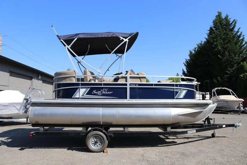Slide: The Image of 2025 Sun Chaser Vista Fish 18 pontoon boat on trailer, parked outdoors. - 3