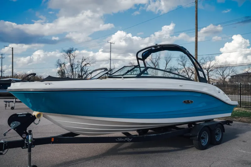 The Image of 2023 Sea Ray SPX 230 boat with blue hull on trailer, parked outdoors. - 0