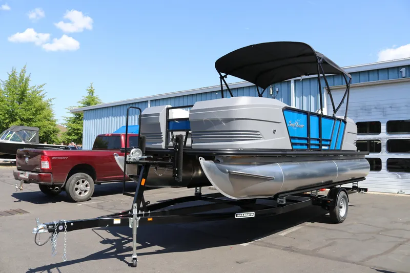 Slide: The Image of 2025 SunChaser Lucerne 20 LR DH pontoon boat on trailer, parked outdoors. - 2