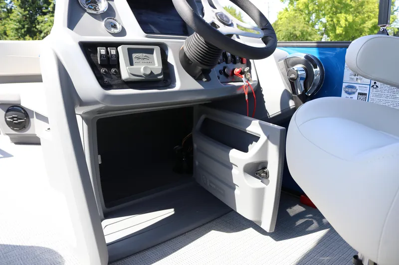 Slide: The Image of 2025 SunChaser Lucerne 20 LR DH boat dashboard with open storage compartment and steering wheel. - 21