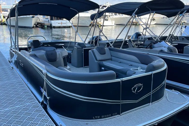 Slide: The Image of 2023 Tahoe Pontoon LTZ Cruise boat docked at marina, featuring sleek design and spacious seating. - 2
