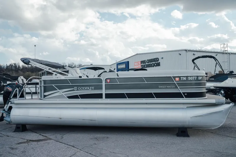 The Image of 2023 Godfrey Sweetwater 2286 C pontoon boat parked outside showroom under cloudy sky. - 0