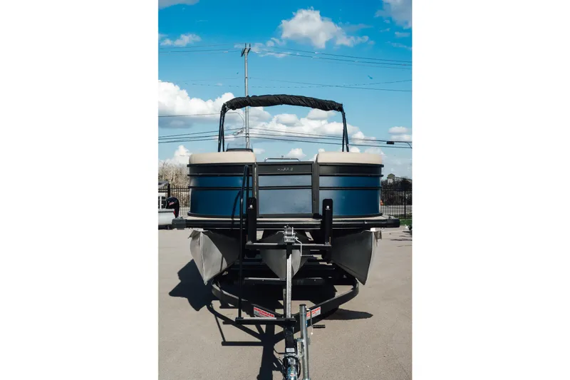 Slide: The Image of 2024 Harris Cruiser 230 pontoon boat on trailer under blue sky. - 3