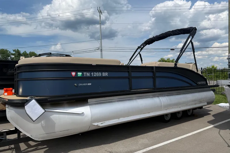 Slide: The Image of 2024 Harris Cruiser 230 pontoon boat parked outdoors under cloudy sky. - 9