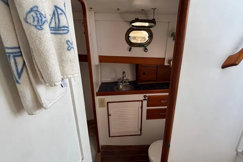 Slide: The Image of Compact boat bathroom with sink, porthole, and nautical-themed towels on a Jarvis Newman 36, 1985. - 37