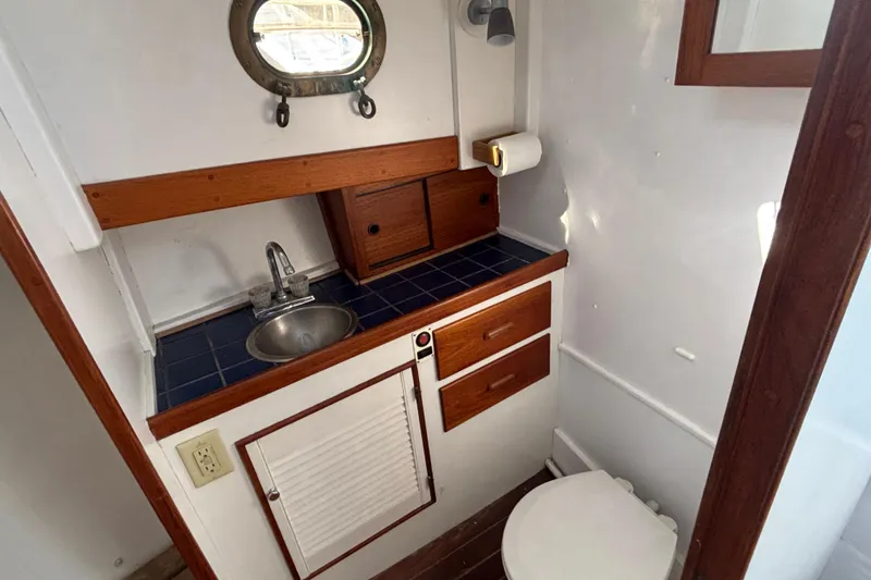 Slide: The Image of 1985 Jarvis Newman 36 boat bathroom with sink, wooden cabinets, and porthole window. - 38