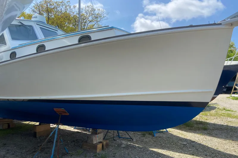 Slide: The Image of 1985 Jarvis Newman 36 boat on stands, white hull with blue bottom, outdoors. - 63