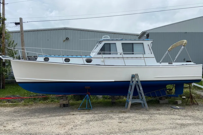 Slide: The Image of 1985 Jarvis Newman 36 boat on dry dock, white hull, blue bottom, near industrial building. - 64