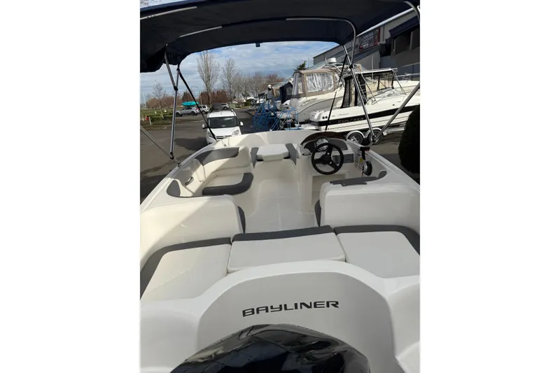 Slide: The Image of 2019 Bayliner Element E16 boat interior with seating and steering wheel, docked outdoors. - 3