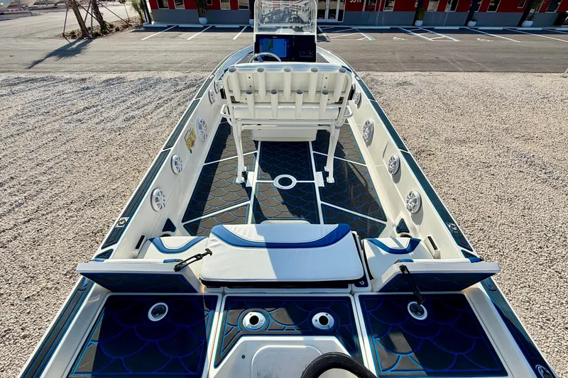Slide: The Image of 2020 Skeeter SX230 boat interior with blue accents and seating, parked on gravel. - 20