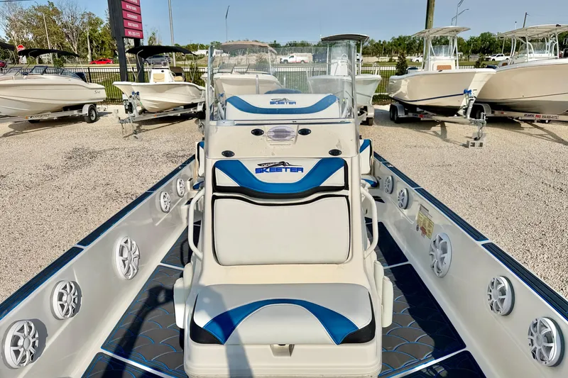 Slide: The Image of 2020 Skeeter SX230 boat interior with blue and white seating, parked among other boats. - 9