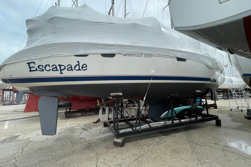Slide: The Image of 1999 Hunter 380 sailboat "Escapade" covered and docked on a stand in a marina. - 2