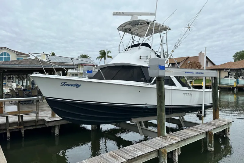 The Image of 1975 Bertram 31 boat named "Tenacity" docked at a marina with overcast skies. - 1