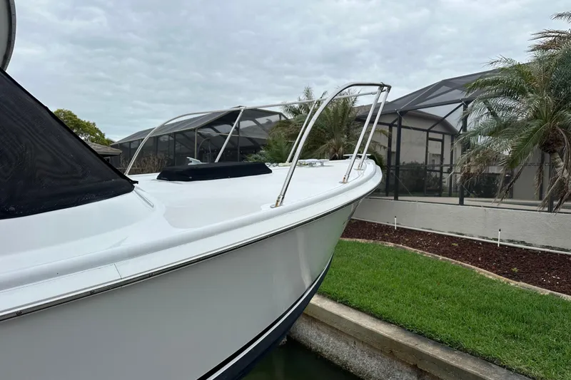 Slide: The Image of 1975 Bertram 31 boat docked near a modern house with palm trees. - 10