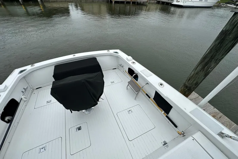 Slide: The Image of 1975 Bertram 31 boat deck with covered seating, docked by calm waters. - 12