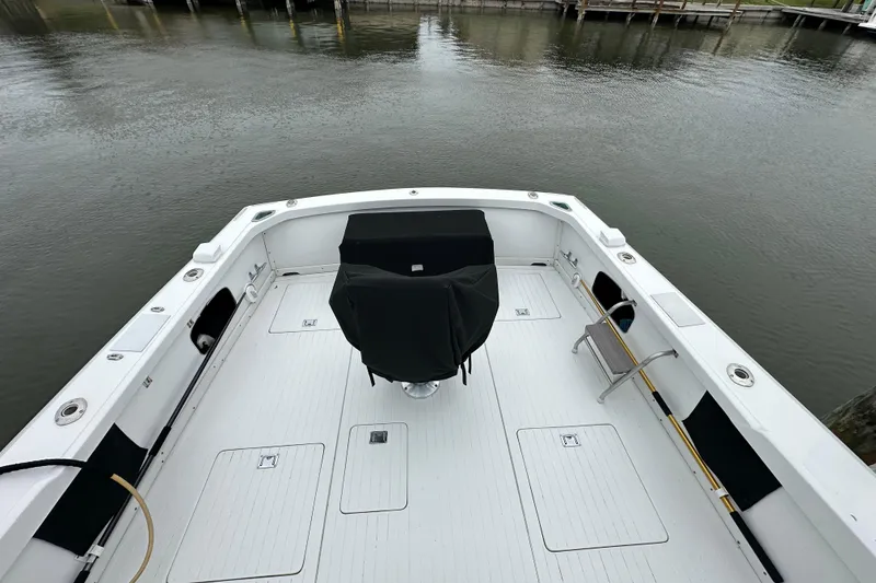 Slide: The Image of 1975 Bertram 31 boat deck with covered seating, docked by calm waters. - 13