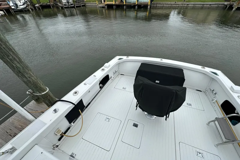 Slide: The Image of 1975 Bertram 31 boat deck with covered seating, docked by calm waters. - 14