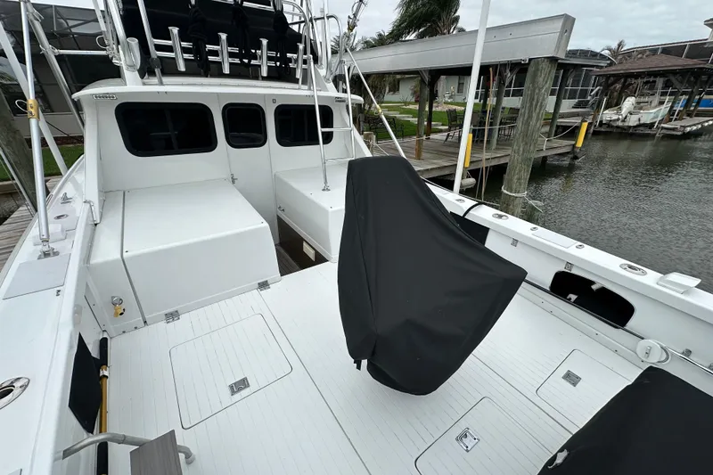 Slide: The Image of 1975 Bertram 31 boat deck with covered seating, docked by a waterfront. - 15