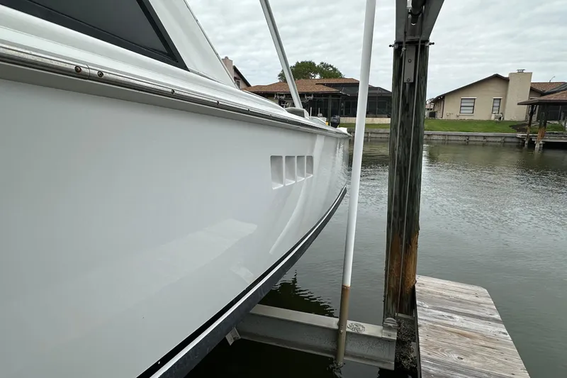 Slide: The Image of 1975 Bertram 31 boat docked by waterfront homes under cloudy sky. - 3