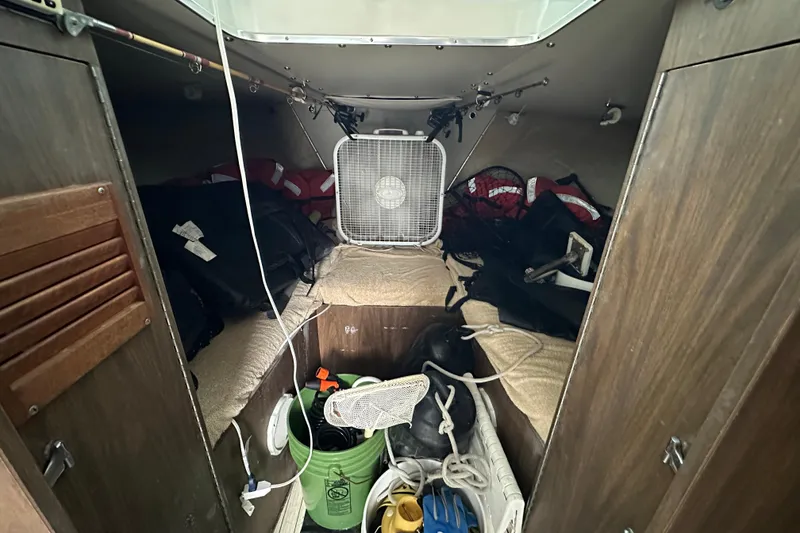 Slide: The Image of 1975 Bertram 31 cabin interior with fan, life jackets, and storage items. - 34