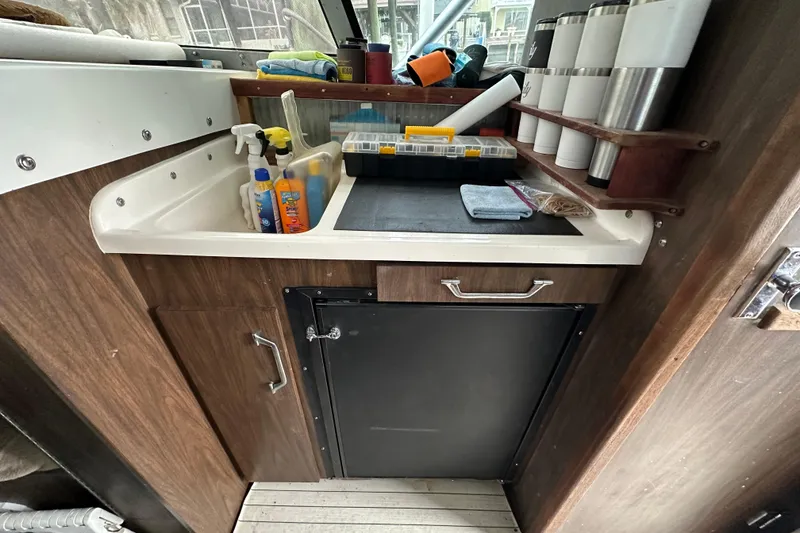 Slide: The Image of 1975 Bertram 31 boat interior with sink, storage, and organized supplies. - 35