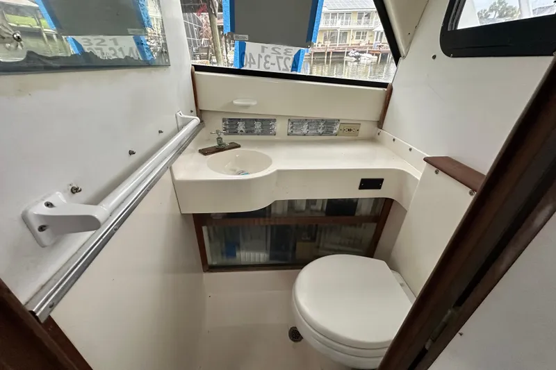 Slide: The Image of 1975 Bertram 31 boat bathroom with sink, toilet, and window view. - 37
