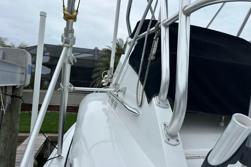 Slide: The Image of 1975 Bertram 31 boat with metal railings and black cover, docked near greenery. - 47