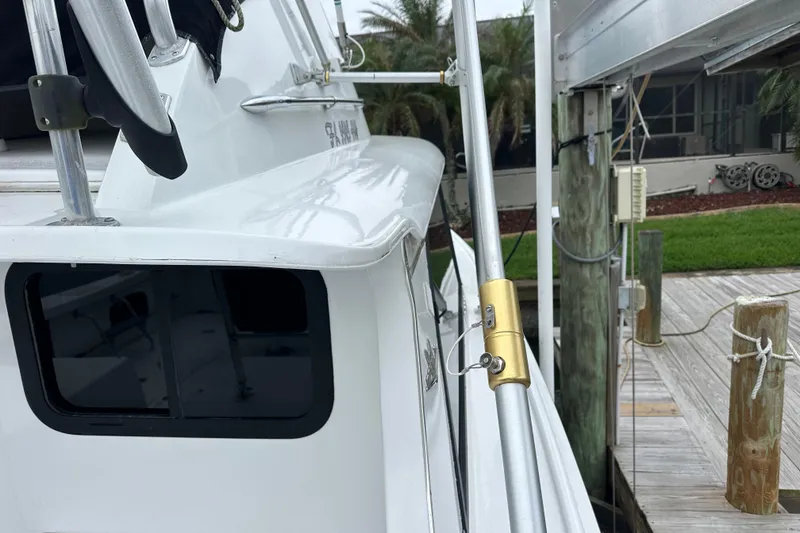 Slide: The Image of 1975 Bertram 31 boat docked, showcasing sleek white exterior and fishing equipment. - 49