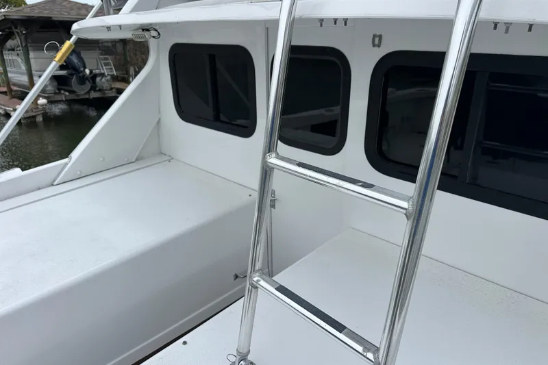 Slide: The Image of 1975 Bertram 31 boat deck with ladder and windows, docked near water. - 51